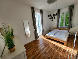a bedroom with a bed and wooden floors and windows at Suite 3 - Apartments am Schloss in Oberschleißheim