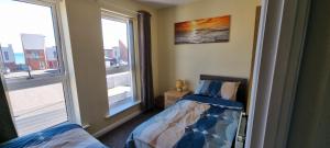 una piccola camera con due letti e due finestre di Sunrise Cottage, 2 minutes walk from the beach! a Woodhorn