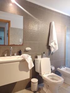 Un baño con inodoro, lavabo y espejo. en Belgrano 210, en Canals