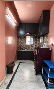 a kitchen with black cabinets and a red wall at Homely Stay in Kolkata