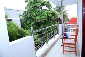 a balcony with a chair and a table and a tree at Urban Elite Home Stay in Puducherry