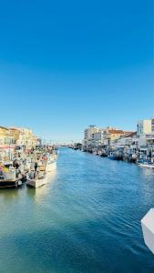 een groep boten aangemeerd in een rivier met gebouwen bij Appartement Chic 50m de la mer in Palavas-les-Flots