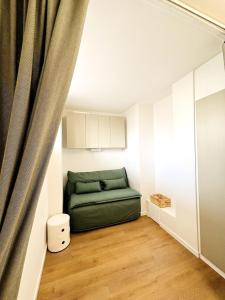 een woonkamer met een groene bank en een gordijn bij Appartement Chic 50m de la mer in Palavas-les-Flots