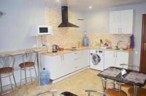a kitchen with white cabinets and a table and a microwave at Hostel VIP Na Pestelya, 11 in Vinnytsya