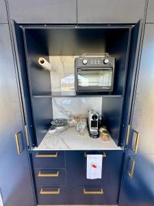 a small blue cabinet with a toaster oven in it at Self-contained tiny home on acreage - 16 Belleview Dr in Murrumbateman +19 photos