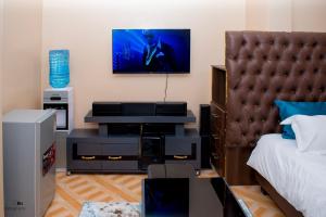 a bedroom with a bed and a tv on the wall at The Ehajis Exclusive Studio Apartment in Elgon View Near Sports Club, Eldoret in Eldoret