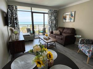 a living room with a couch and a table with flowers at 453 Shore Fun Oceanfront Great Location in Myrtle Beach