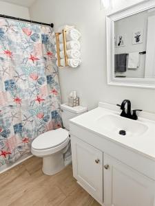 een badkamer met een toilet, een wastafel en een douchegordijn bij Out To Sea - Oceanfront 2 Bedroom, 2 Bath Condo in North Topsail Beach +32 foto's