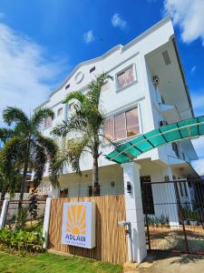公主港Adlaw Inn的一栋白色建筑，前面有一棵棕榈树