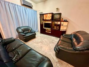 a living room with two leather chairs and a television at The Yew Homestay in Teluk Intan +12 photos
