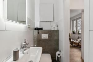 a white bathroom with a sink and a mirror at SHINY HOMES - Trendy Apartment Close to City Center in Bielefeld