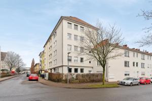 a white building with cars parked in front of it at SHINY HOMES - Trendy Apartment Close to City Center in Bielefeld