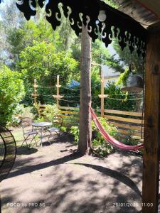 a hammock in a garden with a table and a tree at El Tambucho Miramar BsAs in Miramar
