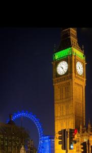 a clock tower with the london eye in the background at Good Charming Apartment in London