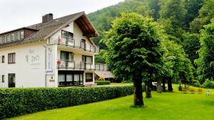 a large white building with a tree in the yard at Harz hotel Iris in Sieber