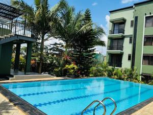 a swimming pool in front of a building with palm trees at Bellwether Apartments in Kampala