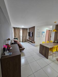 a living room with a table and yellow chairs at Ap. Novo Maceió - praia de Ponta verde in Maceió