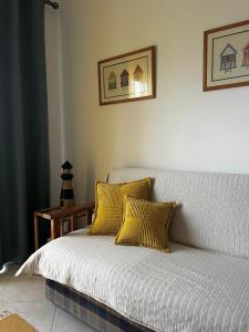 un sofá blanco con almohadas amarillas en una habitación en Casinha das Memórias, en Vieira de Leiria
