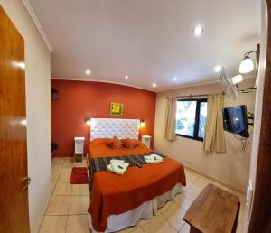 een slaapkamer met een bed met oranje muren bij Cabaña La Pinta in Santa Teresita
