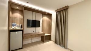 a living room with a tv and a television console in a room at Barelang Hotel Nagoya Batam in Nagoya