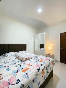 a bedroom with a large bed with a floral bedspread at Homestay Griya Manggisan in Banyurojo +9 photos