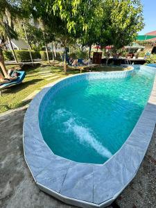 una gran piscina con agua azul en un patio en BaanSuan Marigold บ้านสวนมาลีโกลด์, en Ban Madua Chumphon