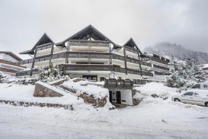 a large building in the snow with a car parked in front at Attic Apartment Dolasilla in Selva di Val Gardena