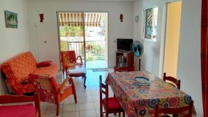 a living room with a table and chairs and a television at T2 Bas de villa Les Hibiscus in Sainte-Anne