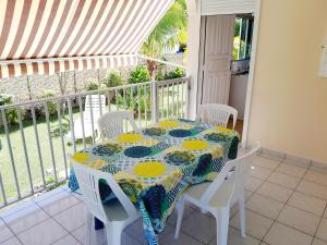 a table and chairs on a balcony with a view of the ocean at T2 Bas de villa Les Hibiscus in Sainte-Anne