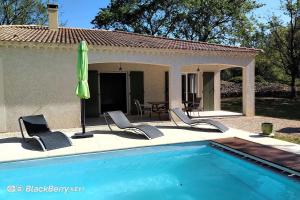 a pool with chairs and an umbrella next to a house at Belle maison avec piscine et terrain entièrement clôturé in Saint-Privat-de-Champclos