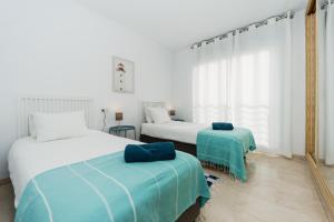 2 Betten in einem weiß-blauen Zimmer in der Unterkunft Blue Nautico - penthouse with stunning views of La Herradura in La Herradura