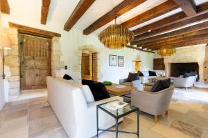 a living room with white furniture and a stone wall at Château de Belet in Saint-Aquilin