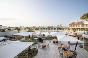 an outdoor patio with tables and umbrellas and a pool at Fantinello Hotel in Caorle