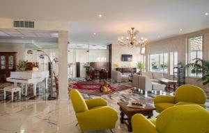 a living room with yellow chairs and a piano at Fantinello Hotel in Caorle