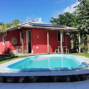 a house with a blue pool in front of a red house at Aquarela Village - Barra Grande in Marau