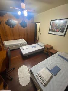 a room with two beds and a table and a mirror at Apto Familiar 4 QUARTOS E 2 BANHEIRO in Uruguaiana