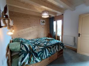 a bedroom with a bed and a wooden wall at Chalet la Belle Verte in Saint-Sigismond