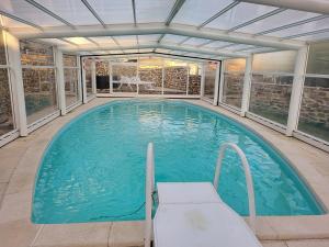 a large swimming pool with a bench in a building at Au Bon Accueil in Bonnac