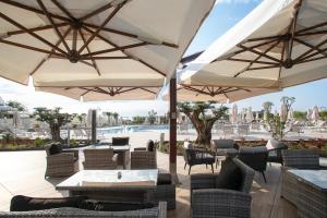 a patio with tables and umbrellas and a pool at Fantinello Hotel in Caorle