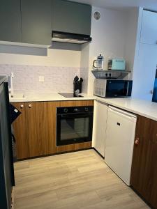a kitchen with wooden cabinets and a black and white dishwasher at Duplex Vielle-Aure in Vielle-Aure +3 photos