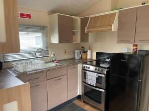 Una cocina con un refrigerador negro y un fregadero. en Cosy 3 Bedroom Caravan, South Cerney, en South Cerney