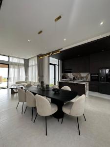 a dining room with a black table and white chairs at Villa Golf Novaworld in Bình Sum