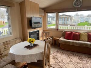 una sala de estar con una mesa y un sofá en Cosy 3 Bedroom Caravan, South Cerney, en South Cerney