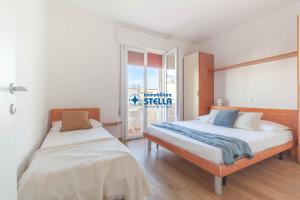 sypialnia z 2 łóżkami i przesuwnymi szklanymi drzwiami w obiekcie Condominio International w mieście Lido di Jesolo
