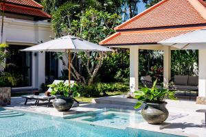 a pool with two umbrellas and a table and chairs at Luxury 4 Bedroom Villa 1 Minute from Laguna Phuket in Bang Tao Beach