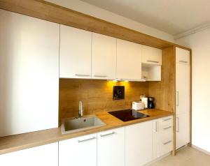 una cucina con mobili bianchi e un lavandino di Bella Vista Green Apartment a Braşov