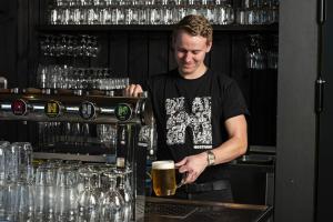 un hombre de pie detrás de una barra preparando una cerveza en New Prague Apartment - Varta Alpha, en Praga