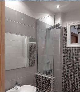 a bathroom with a sink and a shower with a mirror at Dora's house in Perea