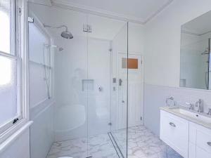 Un baño blanco con ducha y lavabo. en Kent St Townhouse, en Sídney 16 fotos más