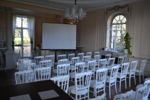 a conference room with white chairs and a projection screen at Le Domaine du Chêne Vert in Château-Gontier